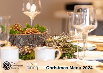 wine glasses, plates and festive pine cone decor on a table